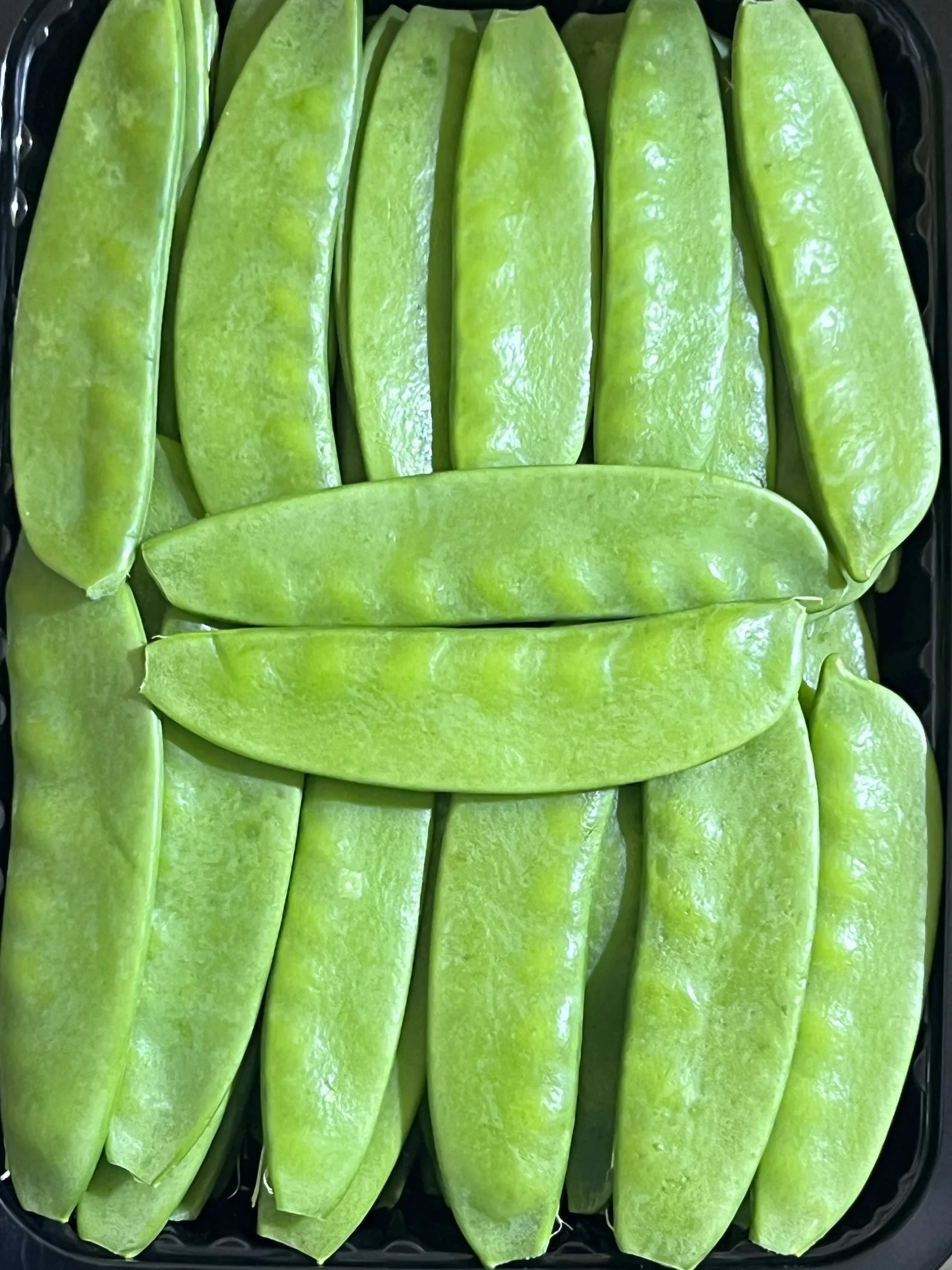 Snow peas (mangetout) packed in a black tray