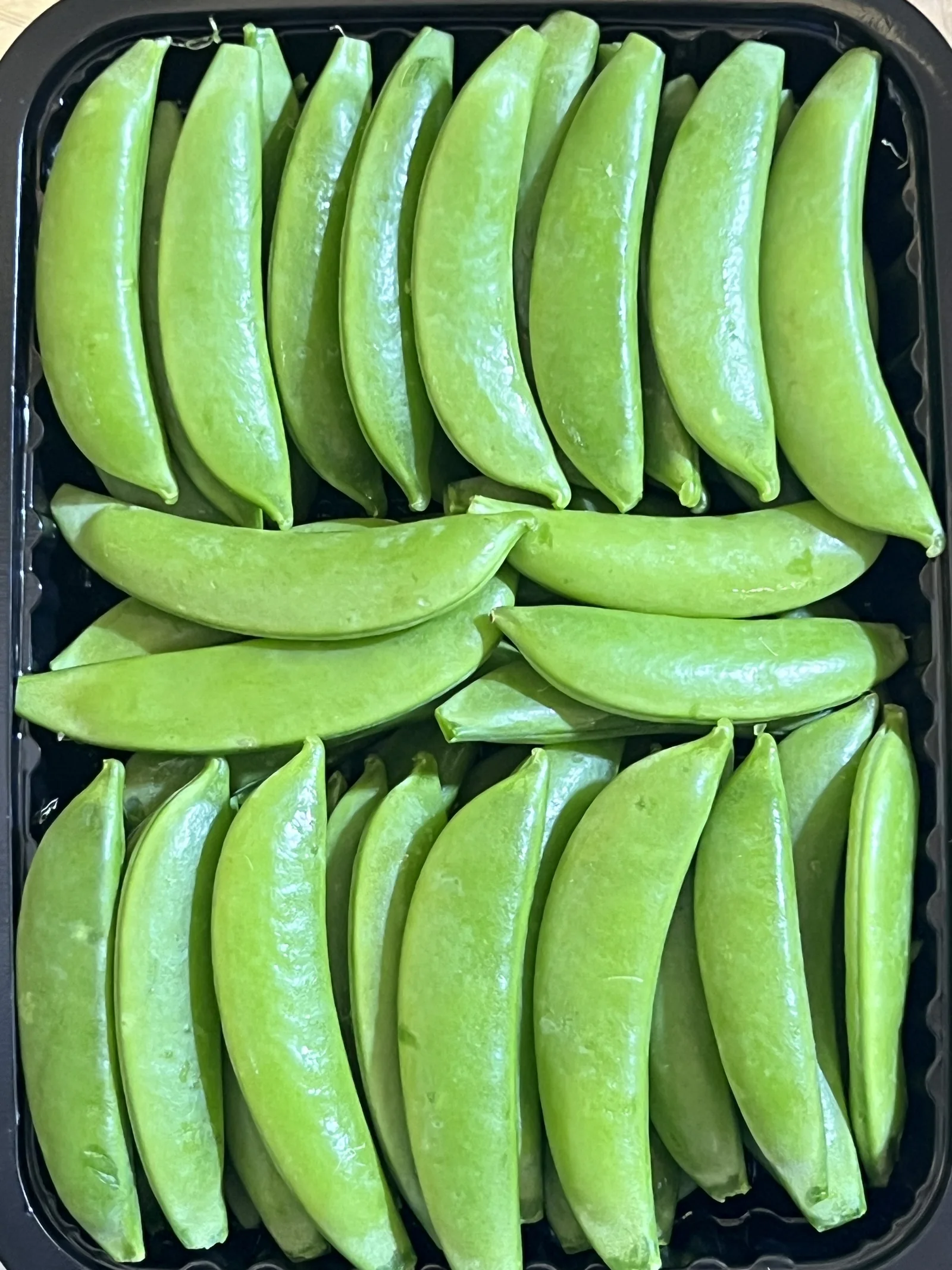 Sugar snap peas packed in a black tray